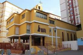 Vista exterior de la Parroquia de San Vicente de Paúl en Málaga, mostrando su fachada amarilla y cruz en la parte superior