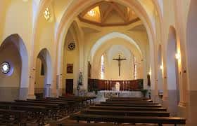 Interior de la iglesia con nave central, bancos y altar principal
