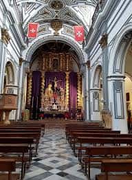 Altar mayor de la Iglesia de San Juan Bautista con retablo dorado y cortinajes púrpuras