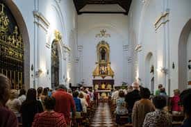 Vista del interior de la nave principal con fieles sentados en los bancos durante una misa