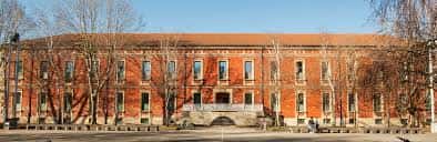 Fachada lateral de un edificio histórico de la UPV/EHU con árboles sin hojas
