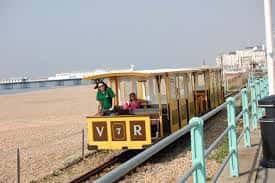 Vagón del tren con pasajeros y vista del paseo marítimo