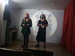 Escenario del evento con dos personas presentando frente a una proyección circular