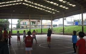 Pabellón deportivo cubierto del colegio con niños jugando al baloncesto
