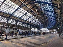Vista panorámica del andén principal de la estación con techo de cristal y estructura metálica azul