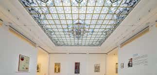 Interior del centro cultural con techo de cristal decorativo y paredes blancas