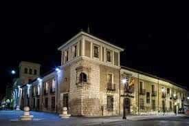 Vista nocturna del Palacio de Pimentel con fachada iluminada y banderas españolas