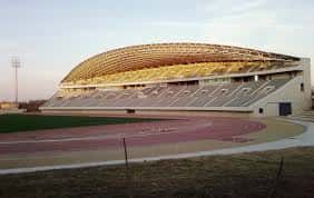 Vista exterior del Estadio de Atletismo Ciudad de Málaga con su característica cubierta curva y gradas al atardecer