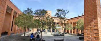 Patio interior de la Facultad con árboles, bancos y estudiantes en un ambiente tranquilo