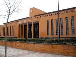 Fachada lateral de la Facultad de Letras con muro bajo y vegetación en primer plano