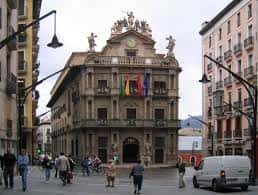 Vista frontal del Ayuntamiento de Pamplona con banderas y personas caminando