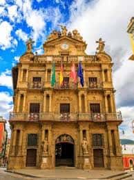 Detalle arquitectónico del Ayuntamiento de Pamplona con banderas y cielo nublado