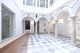 Patio interior del palacio con arcos, columnas y suelo de baldosas a cuadros