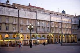 Plaza de Carlos I en A Coruña con edificios históricos y arcos iluminados al atardecer
