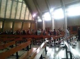Interior de la iglesia con bancos de madera y luz natural entrando por ventanas altas