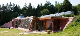 Vista exterior del Earthship Brighton con fachada de ladrillo y paneles solares integrados