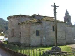 Vista lateral de la Iglesia de San Salvador de Coruxo con cruz de piedra al frente