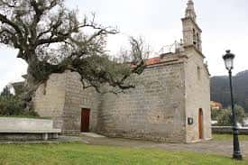 Fachada principal de la iglesia con árbol antiguo y farola tradicional