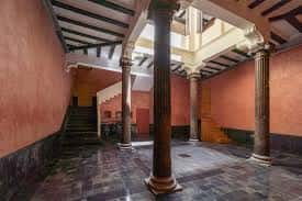 Interior del patio central con columnas de piedra y escalera de acceso