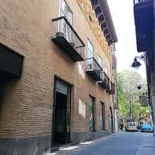 Fachada lateral del palacio en calle estrecha con vegetación urbana