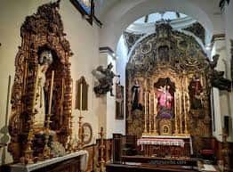 Vista del interior de la iglesia con dos retablos ornamentados y altar principal