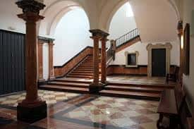 Escalera principal del hall de entrada con columnas de madera y suelo de mosaico