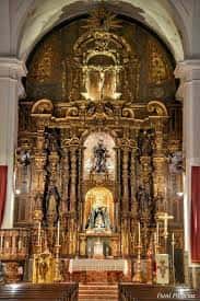 Detalle del retablo mayor barroco con esculturas y decoración dorada