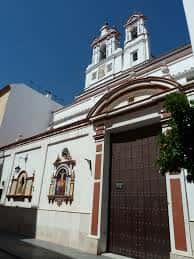 Fachada principal de la iglesia con puerta de madera y torres gemelas bajo cielo azul