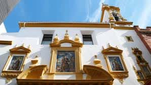 Vista elevada de la fachada principal con ornamentos dorados y campanario bajo cielo azul