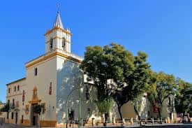 Vista exterior de la Iglesia de San Benito en Sevilla con su torre y fachada blanca bajo cielo azul