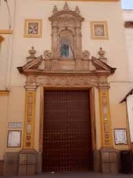 Fachada principal de la Real Iglesia de San Antonio Abad con puerta de madera y nicho superior