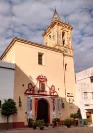Fachada principal de la Basílica de María Auxiliadora en Sevilla con detalles arquitectónicos y cielo nublado
