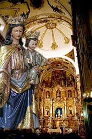 Estatua de la Virgen María con el Niño Jesús en el interior de la Basílica, con retablo dorado al fondo