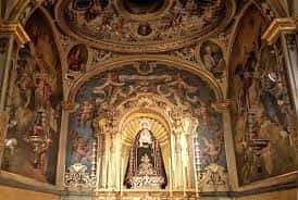 Interior de la capilla con retablo barroco y pintura mural decorativa