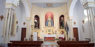 Vista del altar principal con imágenes religiosas y bancos de madera
