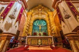Interior de la basílica con altar dorado y retablo central iluminado