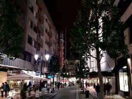 Vista nocturna de la Calle Gil de Jaz con terrazas y peatones, mostrando ambiente urbano y comercial