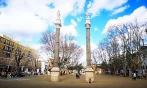 Vista diurna de la Alameda de Hércules con sus dos columnas monumentales bajo cielo azul