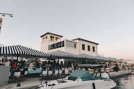 Vista del restaurante Lamucca del Mar junto al muelle con mesas al aire libre y embarcaciones