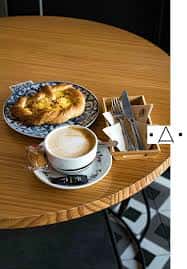 Detalle de mesa con café y bollería en el interior del gastrobar