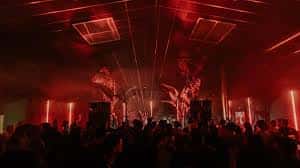 Escenario del club con iluminación roja y efectos de láser durante un evento nocturno