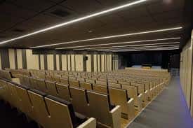 Interior del auditorio con butacas de madera y escenario iluminado
