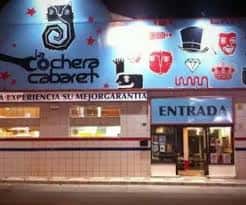 Fachada nocturna de La Cochera Cabaret con letrero iluminado y entrada