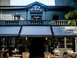 Fachada exterior del local No32 en Brighton con toldos y mesas al aire libre