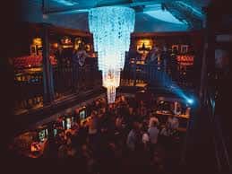 Interior del venue No32 con iluminación ambiental, lámpara de araña y público en evento