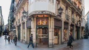 Vista exterior de la librería Elkar en esquina de calle, con letrero luminoso y ambiente urbano