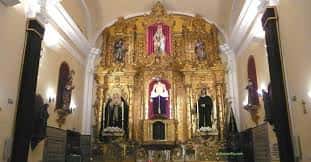Interior de la capilla con retablo dorado y altar principal