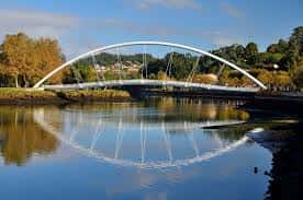 Puente moderno arqueado reflejado en las aguas tranquilas del río Lérez