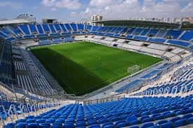 Vista panorámica del interior del Estadio La Rosaleda con gradas azules y campo de césped