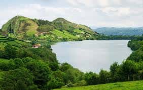 Vista panorámica del Embalse de Los Alfilorios rodeado de colinas verdes y cielo nublado